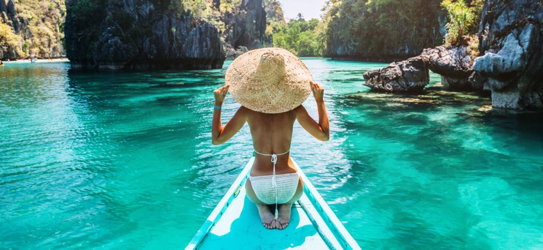 Back view of a woman on a boat enjoying a luxury travel experience on a tropical island
